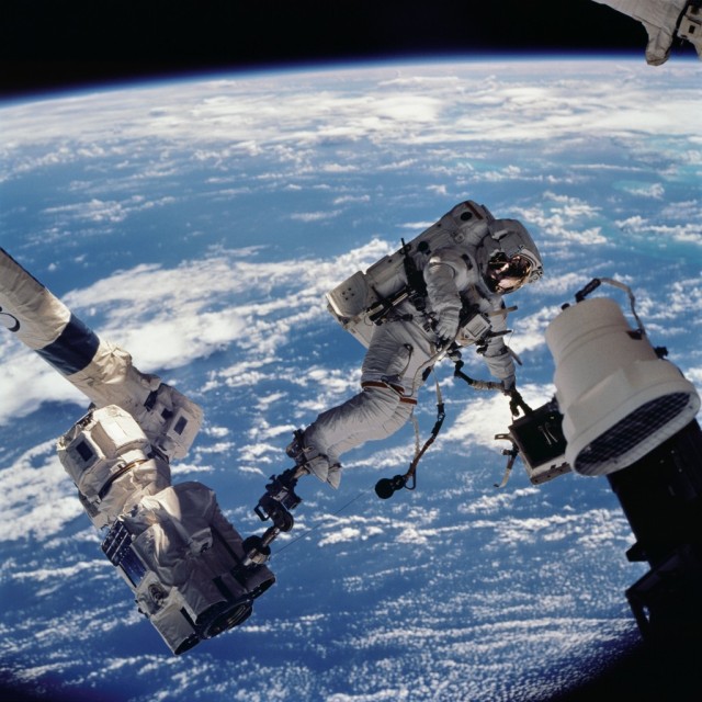 Astronaut David A. Wolf, STS-112 mission specialist, anchored to a foot restraint on the Space Station Remote Manipulator System (SSRMS) or Canadarm2, carries the Starboard One (S1) outboard nadir external camera.