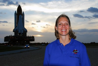 Space Shuttle Discovery Flow Director Stephanie Stilson poses with the orbiter in the background as it is moved from the Vehicle Assembly Building to Launch Pad 39A.