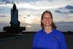 Space Shuttle Discovery Flow Director Stephanie Stilson poses with the orbiter in the background as it is moved from the Vehicle Assembly Building to Launch Pad 39A.