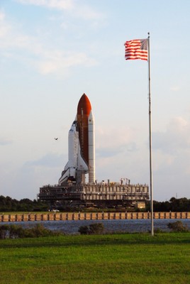 Space Shuttle Discovery moves along the crawlerway near the turn basin in Launch Complex 39 toward Pad A as the sun rises on a balmy Florida morning.