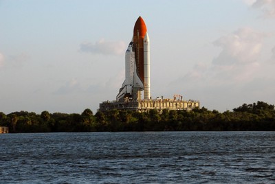 Space Shuttle Discovery, atop a mobile launch platform, passes by the turn basin in Launch Complex 39 toward Pad A as the sun rises on a balmy Florida morning.