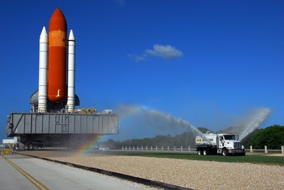 A rainbow can be seen in the spray from the water truck traveling ahead of Space Shuttle Discovery on its move from the Vehicle Assembly Building to Launch Pad 39A.