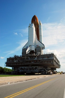 A crawler transporter moves Space Shuttle Discovery, secured atop a mobile launch platform, along the crawlerway from the Vehicle Assembly Building to Launch Pad 39A on a balmy Florida morning.
