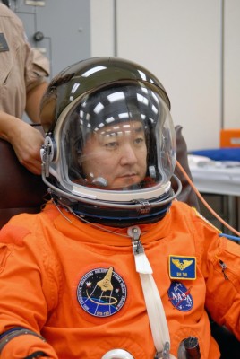 Mission Specialist Daniel Tani has his helmet adjusted during fitting of his launch and entry suit