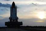 Space Shuttle Discovery moves along the crawlerway from the Vehicle Assembly Building toward Launch Pad 39A as the sun rises on a balmy Florida morning.